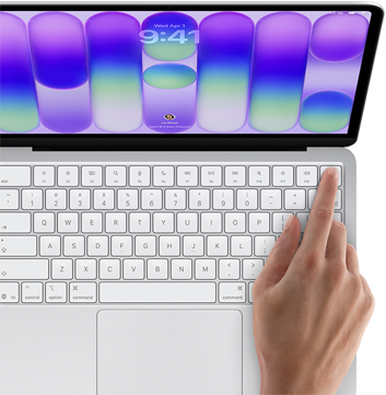 MacBook Neo color argento che mostra la schermata di login, con il dito di una persona appoggiato sul sensore Touch ID nell’angolo in alto a destra della tastiera