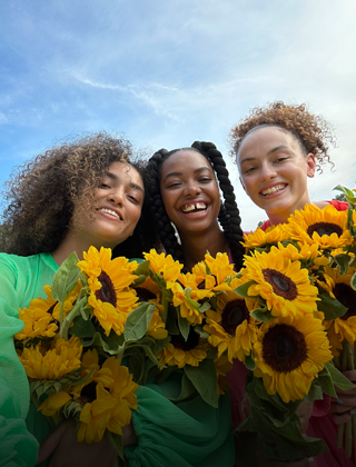 Un selfie nitido e brillante di tre persone che tengono in mano dei fiori.